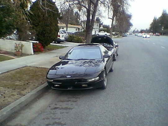 1993 Ford Probe parked on street, hood open on car behind it