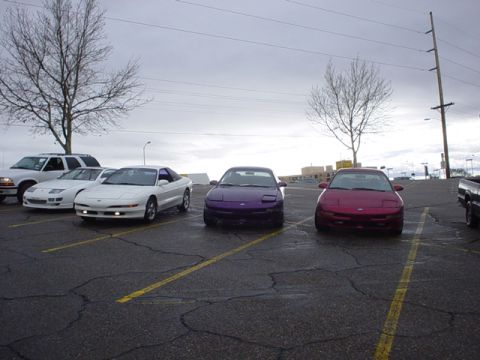 1993 Ford Probe - A trio of Ford Probes, a white, a purple, and a red model, are parked in a lot under an overcast sky.