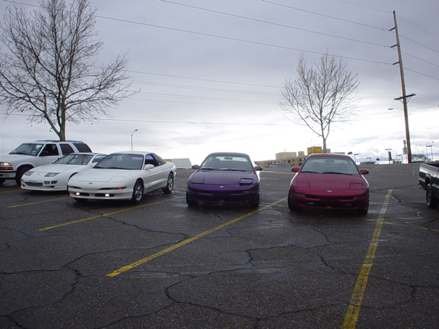 Three 1993 Ford Probes in a parking lot, one white, one purple, one red