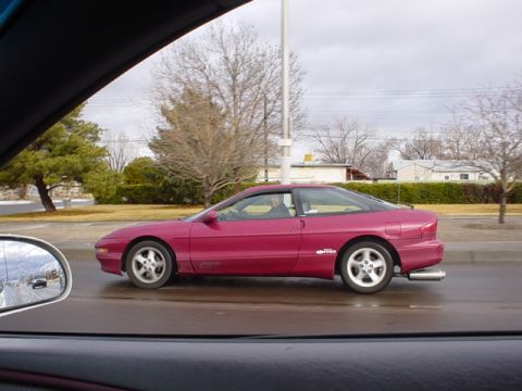 1993 Ford Probe - A red 1993 Ford Probe GT is seen driving on a wet road.