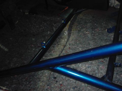 1978 Ford Bronco - Close-up of blue roll cage tubing against a grey carpeted floor inside a vehicle.
