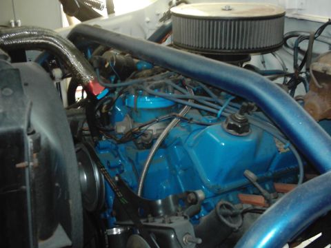 1978 Ford Bronco - The engine bay of a vehicle, showing the blue painted engine block, air filter, and various hoses and wires.