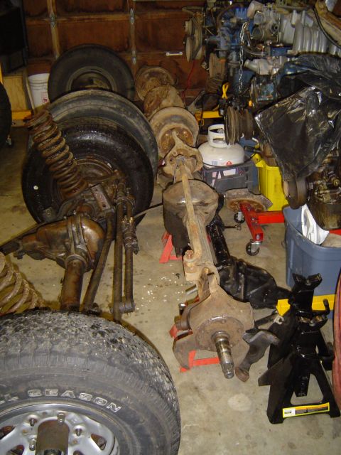 1989 Ford Bronco - Various vehicle axle and suspension components are stored indoors, possibly for repair or restoration.