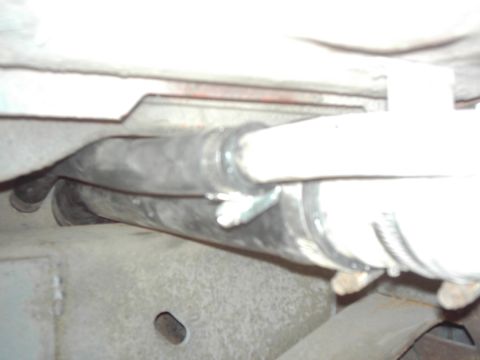 1978 Ford Bronco - Close-up view of an exhaust pipe assembly underneath a vehicle, showing metal clamps securing the hose.