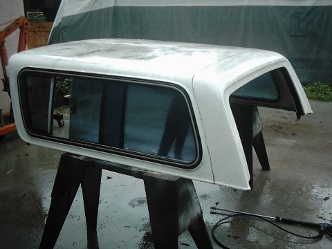 1978 Ford Bronco - White truck cap with tinted windows on sawhorses, possibly for restoration.