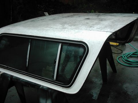 1978 Ford Bronco - Truck bed cap with sliding window, supported by sawhorses outdoors.