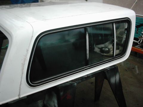 1978 Ford Bronco - A white truck cap is shown from the side, resting on sawhorses for repair or modification.