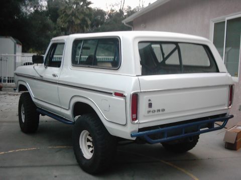 1978 Ford Bronco - Rear view of a white 1978 Ford Bronco blue aftermarket bumpers and a visible interior roll cage.