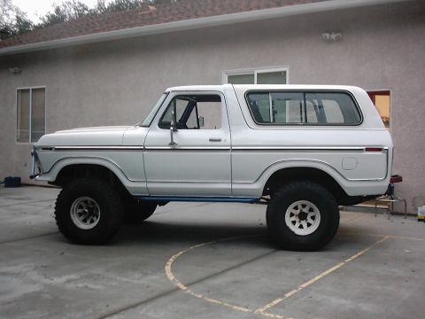 1978 Ford Bronco - This white 1978 Ford Bronco is shown from the side, a lifted suspension and large off-road tires.