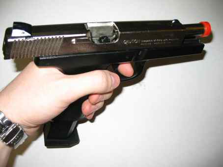 1996 Ford Taurus - A black pistol with an orange tip is held in a hand against a white background. Text at the bottom reads SUPERMOTORS.