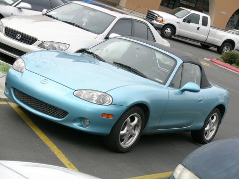 1993 Ford Probe - A light blue convertible sports car is parked in a lot, with other vehicles visible around it.