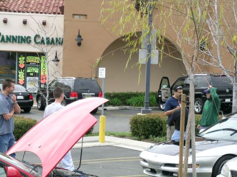 1993 Ford Probe - Several vehicles and people are gathered in a parking lot outside a tanning salon.