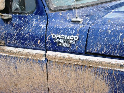 1985 Ford Bronco - Mud splatters cover the side of a blue Bronco Custom F350, obscuring much of its bodywork.