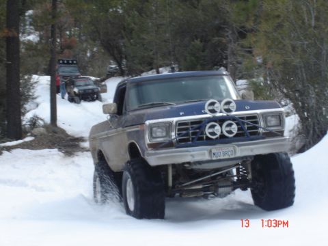 2000 Ford F-450 - Several off-road vehicles navigate a snowy trail in a wooded area.
