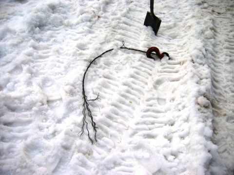 1985 Ford Bronco - Tire tracks are visible in the snow, alongside a shovel and a broken tow strap, suggesting a vehicle may have been stuck.