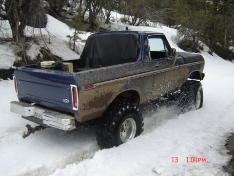 2000 Ford F-450 - A lifted Ford Bronco with large tires navigates a snowy, muddy trail.