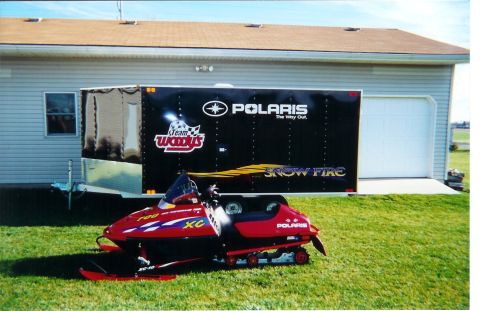 1978 Ford Bronco - A red Polaris snowmobile sits on grass in front of a black trailer with Polaris branding.