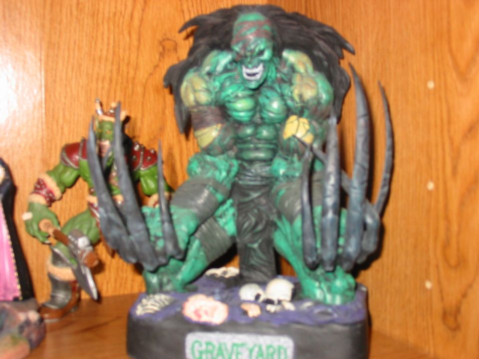Two green monster action figures on a shelf, one with large claws and the other holding an axe
