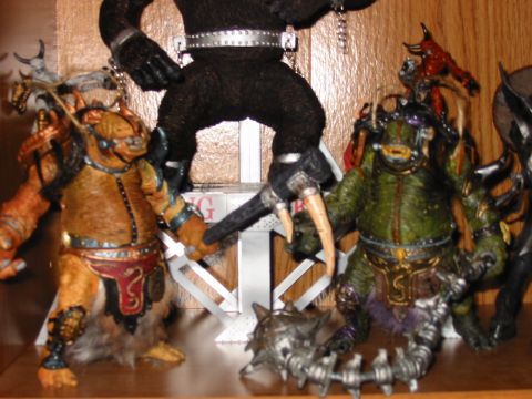 1991 Ford Bronco - A collection of fantasy action figures are arranged on a wooden shelf, with a large ape figure towering over smaller creatures.