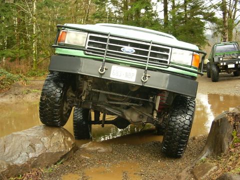 1990 Ford Bronco - This 1990 Ford Bronco is shown tackling a challenging off-road course with another vehicle visible in the background.