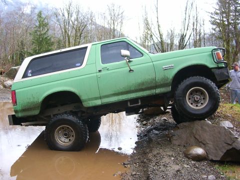 1990 Ford Bronco - 1990 Ford Bronco navigating a challenging off-road obstacle course.