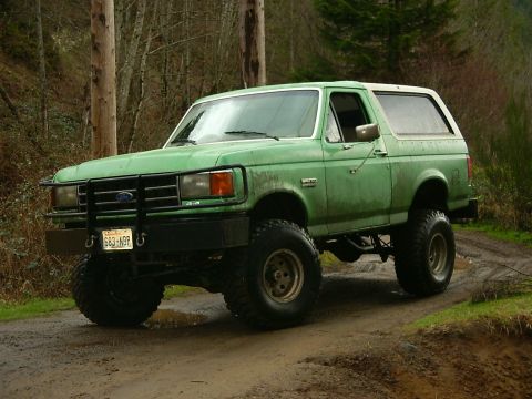 1990 Ford Bronco - Green 1990 Ford Bronco with off-road tires parked on a muddy dirt road.