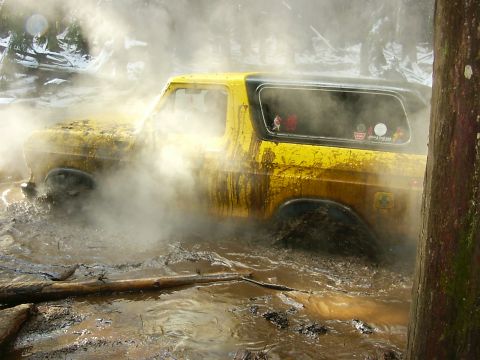 1990 Ford Bronco - This 1990 Ford Bronco is deep in the mud, with steam or smoke obscuring parts of the vehicle.