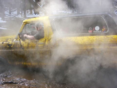 1990 Ford Bronco - A yellow 1978 Ford Bronco navigates a muddy terrain, with steam rising around it.