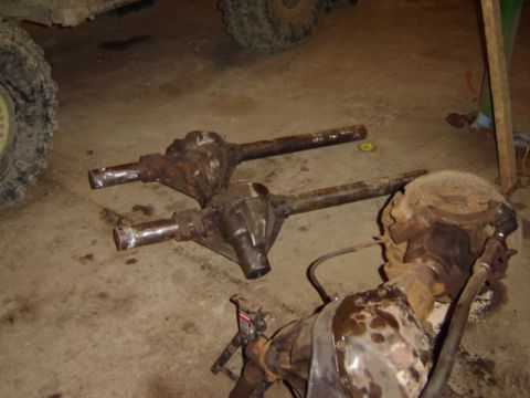 1992 Ford Bronco - Several old, heavily rusted vehicle axles are laid out on a garage floor, suggesting a repair or restoration project.