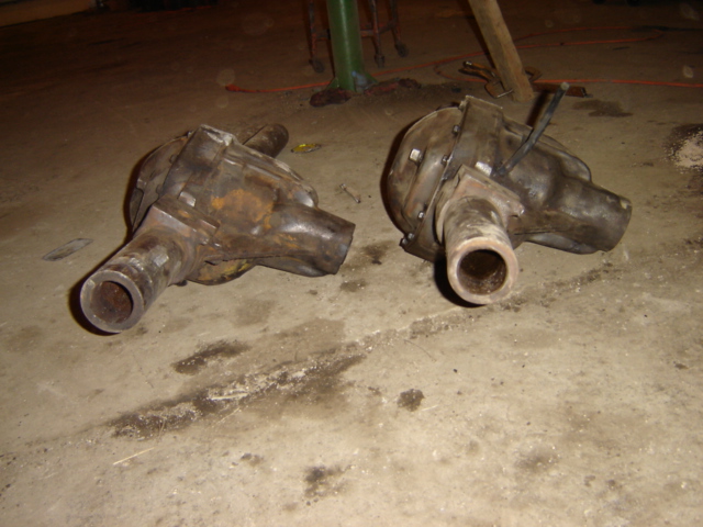 Two rusty differential housings on a concrete floor