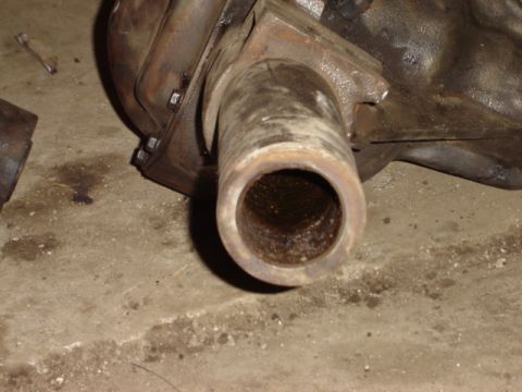 1992 Ford Bronco - Close-up of a rusty metal tube extending from a differential housing on a concrete floor.