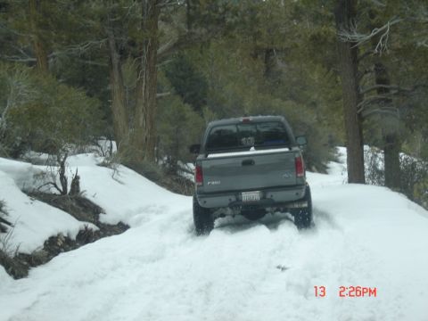 2000 Ford F-450 - A Ford F-250 navigates a snow-covered path through a wooded area.