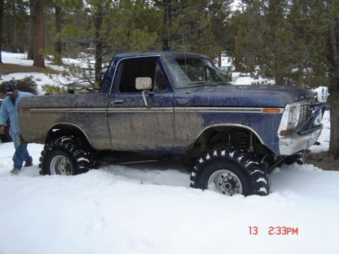 2000 Ford F-450 - A blue Ford pickup truck with large off-road tires is stuck in the snow.