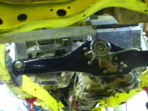 1990 Ford Bronco - Underside view of a vehicle's yellow frame and black suspension parts, with a transmission visible.