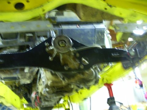 1990 Ford Bronco - Undercarriage view of a yellow vehicle, focusing on suspension components and drivetrain parts.