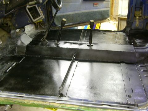 1990 Ford Bronco - Interior floor of a vehicle being prepped for restoration, with new coatings applied to the metal.