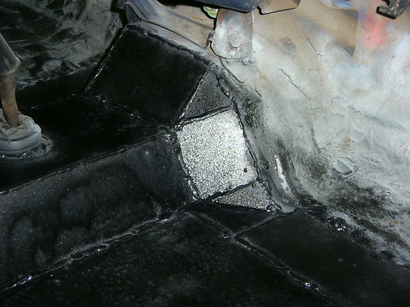 Underbody with black sealant applied to patched metal sections