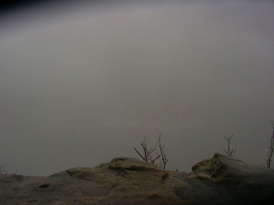 rocky ground with dead branches against a foggy sky, SUPERMOTORS.NET logo in corner