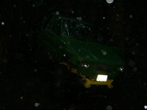 1990 Ford Bronco - A green SUV with a damaged windshield is seen from the front at night, with a yellow tow hitch attached.