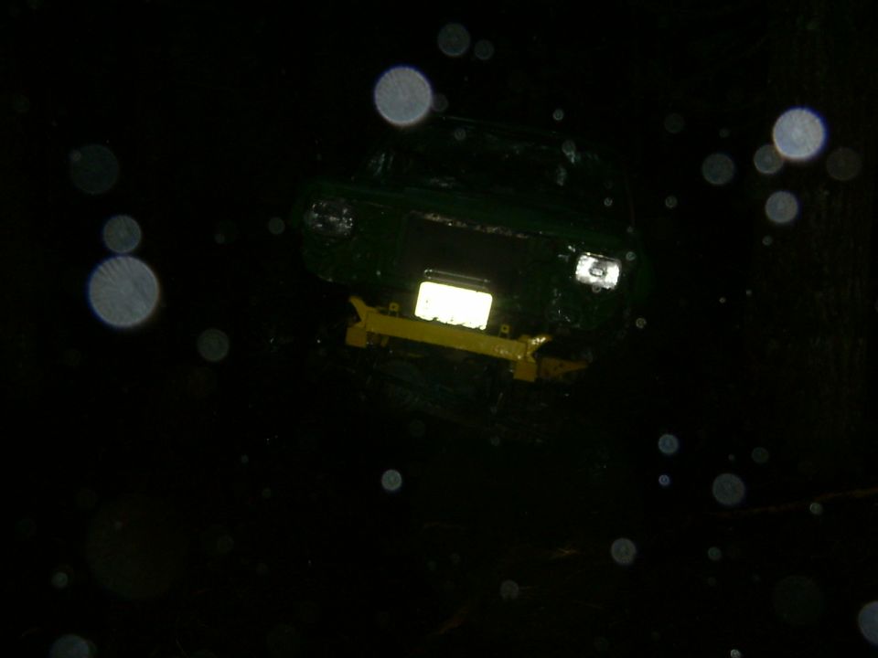 Green vehicle with a yellow bumper and illuminated license plate area