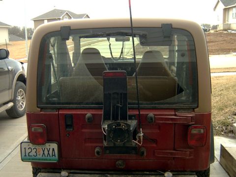 1998 Jeep TJ - Rear view of a red Jeep Wrangler with a tan hardtop, showing the spare tire mount and a license plate.