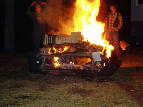 1995 Ford Bronco - Two people watch as a car burns intensely in a yard at night.