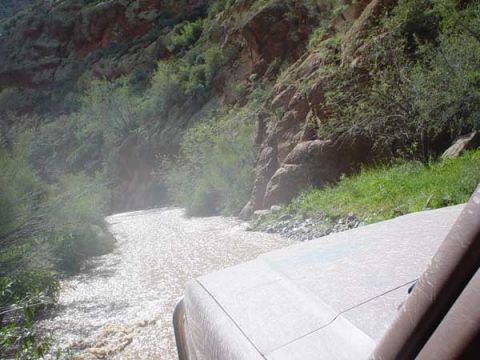 1989 Ford Bronco - A vehicle navigates a riverbed in a , natural landscape.
