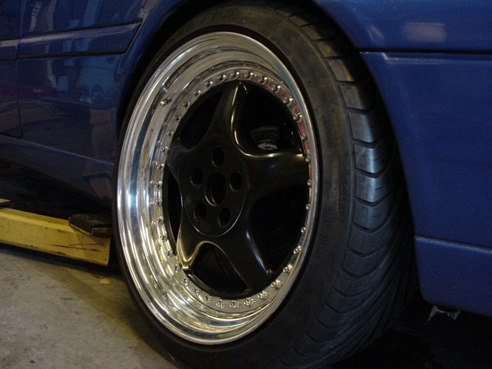 blue car's custom black five-spoke wheel with polished lip and low-profile tire