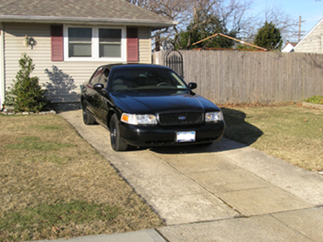 1999 Ford Crown Victoria - A black 1999 Ford Crown Victoria is parked in a driveway in front of a house.