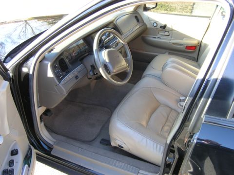 1999 Ford Crown Victoria - The tan leather interior of a 1999 Ford Crown Victoria is visible from the passenger side door.