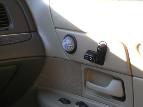 1999 Ford Crown Victoria - Close-up of the interior door panel, showing the speaker grille and power seat adjustment controls.