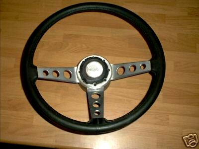 1973 Ford Ranchero - This aftermarket steering wheel features a black rim and three polished metal spokes with circular cutouts.