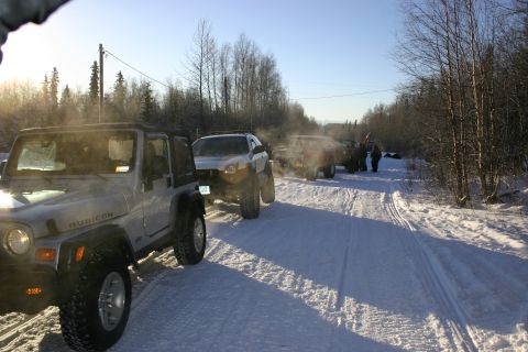 2003 Jeep TJ - Several SUVs, including a 2003 Jeep TJ Rubicon, travel on a snow-covered road in a wooded area.