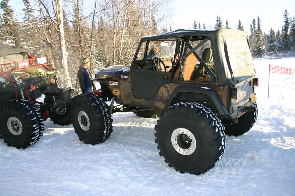 Brown Jeep Wrangler with oversized tires in a snowy landscape